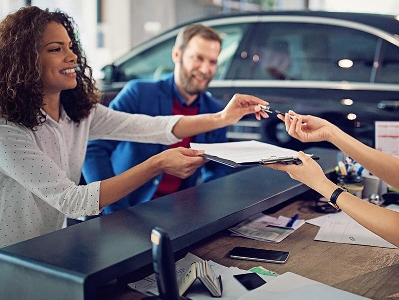 Couple signing finance documents in a dealership