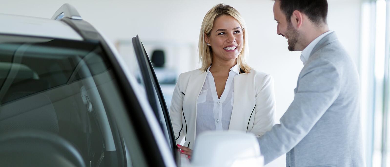 Dealership sales associate showing a customer a new car