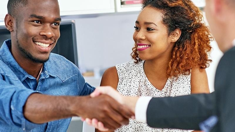 Couple shaking hands with a dealership finance manager