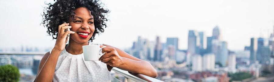 Woman talking on a phone while holding a coffee mug.