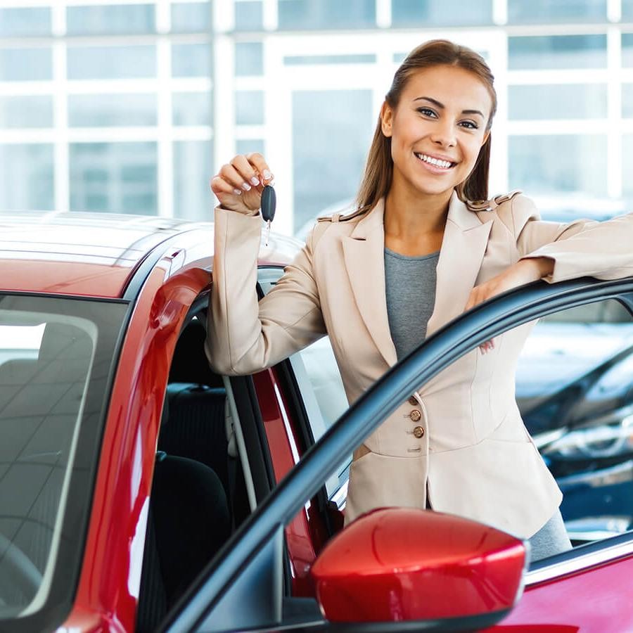 Smiling woman holding keys by a new car