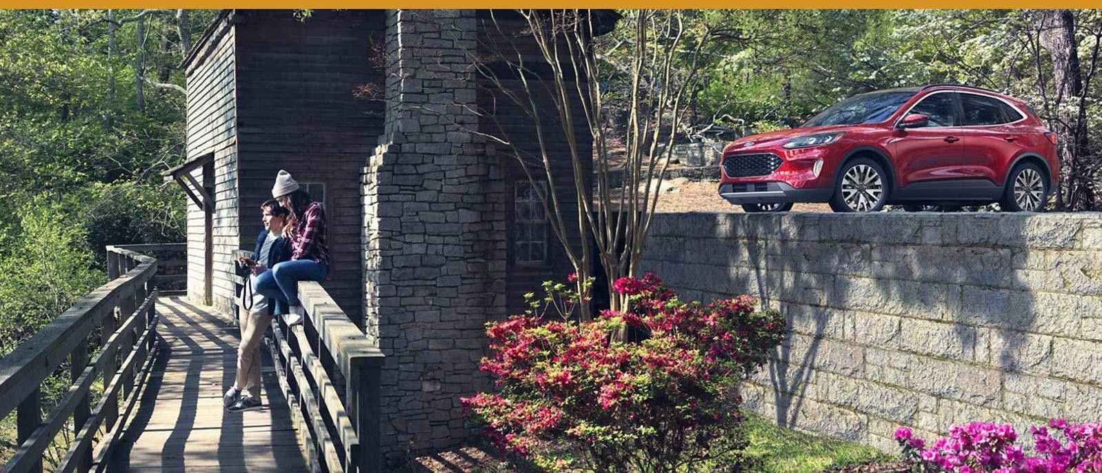 A couple on a walking trail across from a Ford Escape.