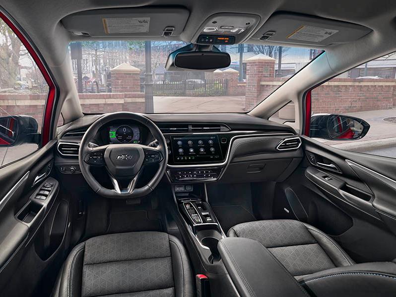 The Interior of a Chevrolet bolt looking out the windshield from the drivers position. Facing the steering wheel and center control panel with screen.