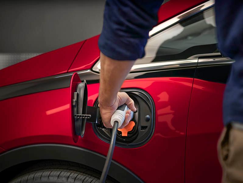 A person plugging in a charging cable in to a Chevrolet Bolt.