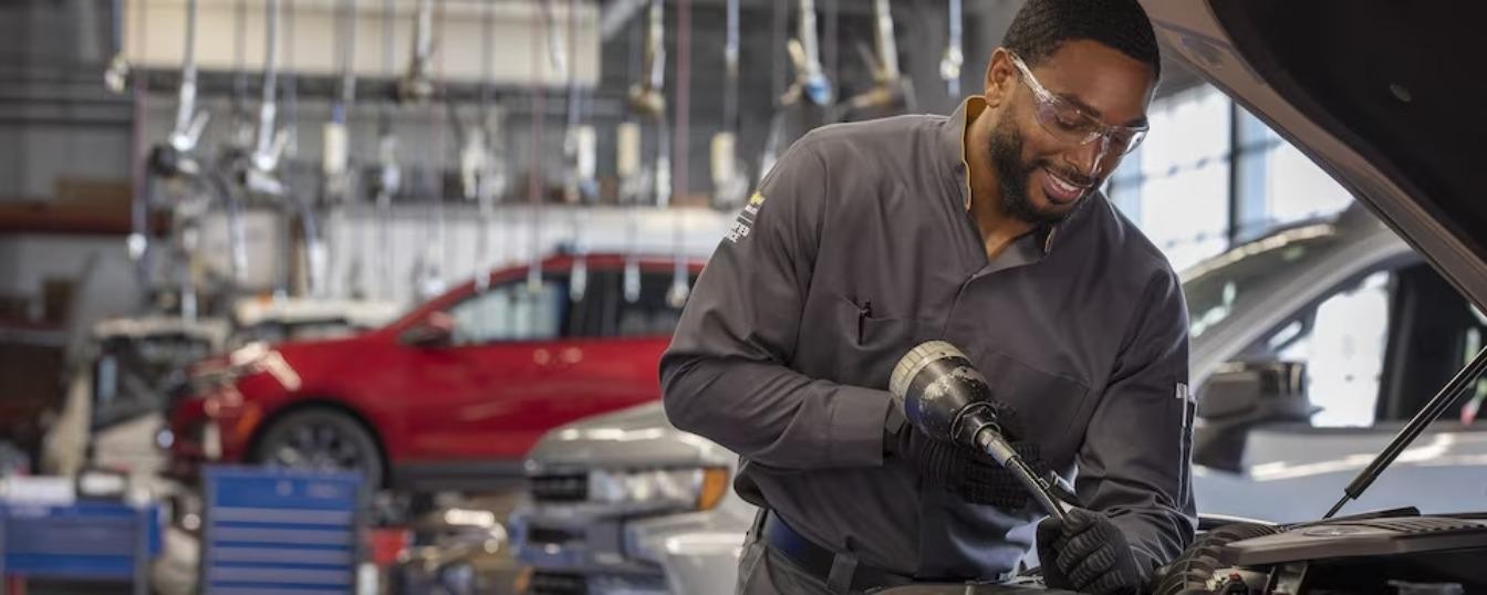 A Chevrolet Service Technician checking the oil level of a vehicle.