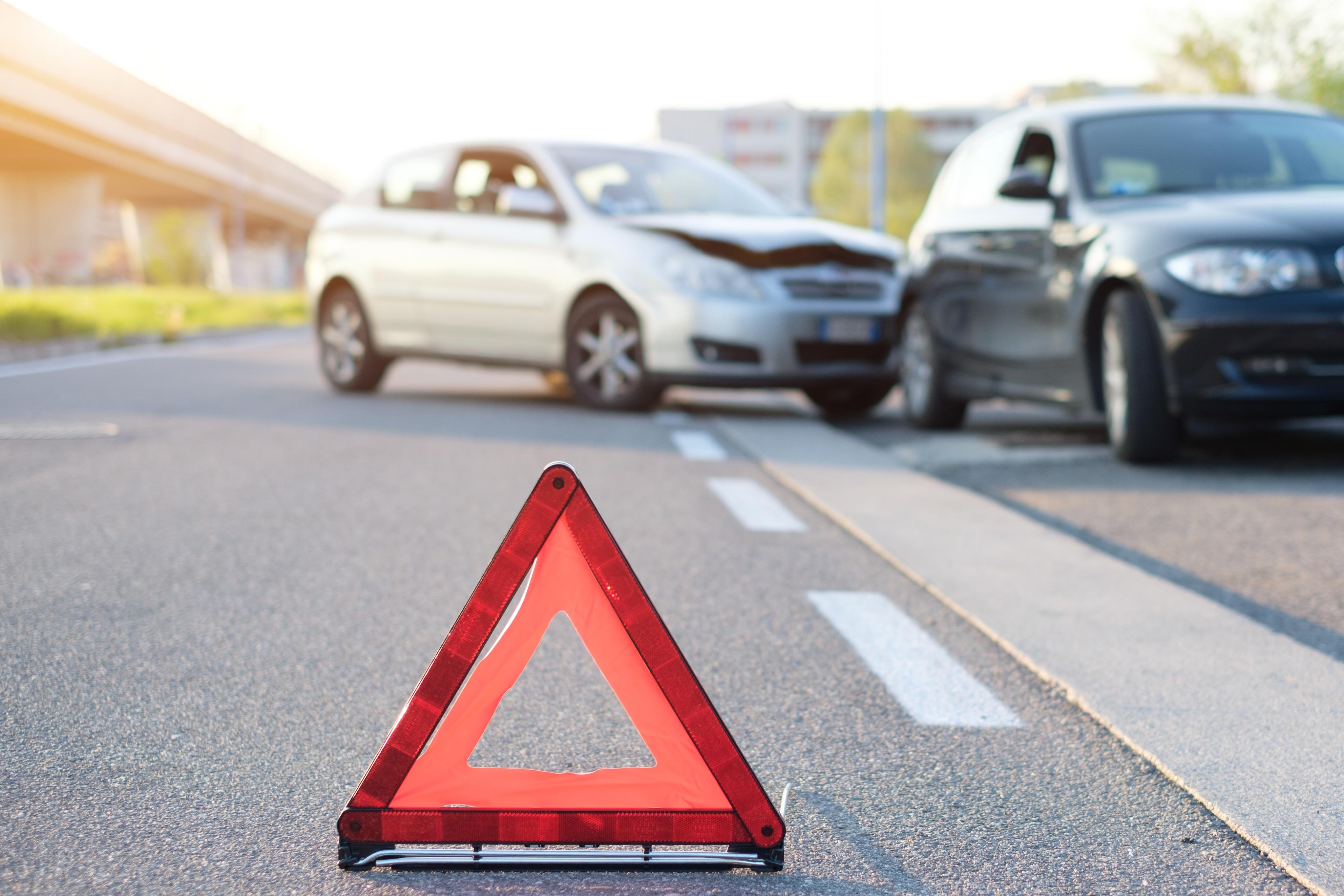 Orange caution triangle blocking two cars in roadside accident