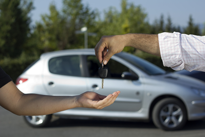 person handing keys to new car owner