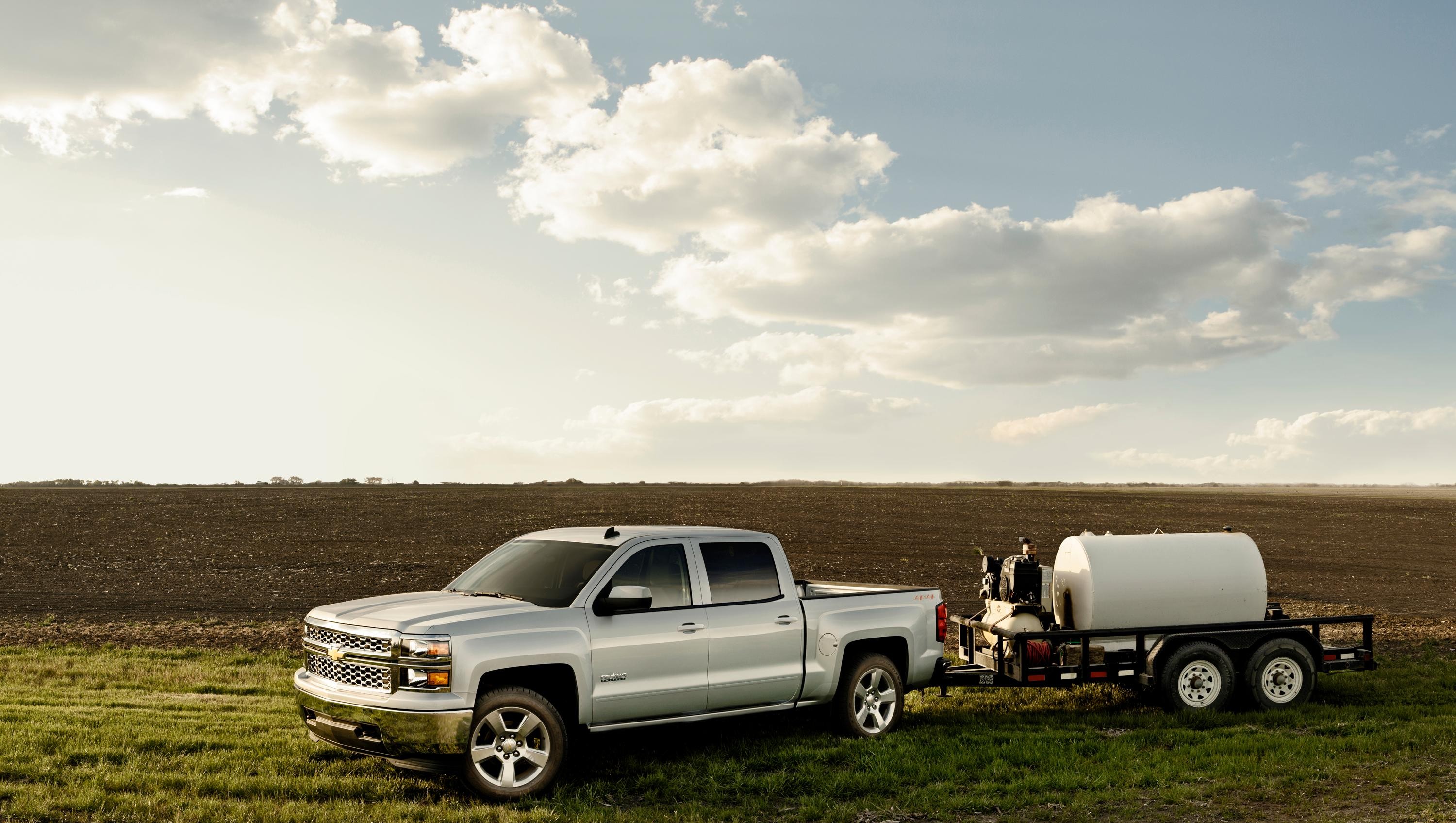 White Chevy Silverado towing farming equipment