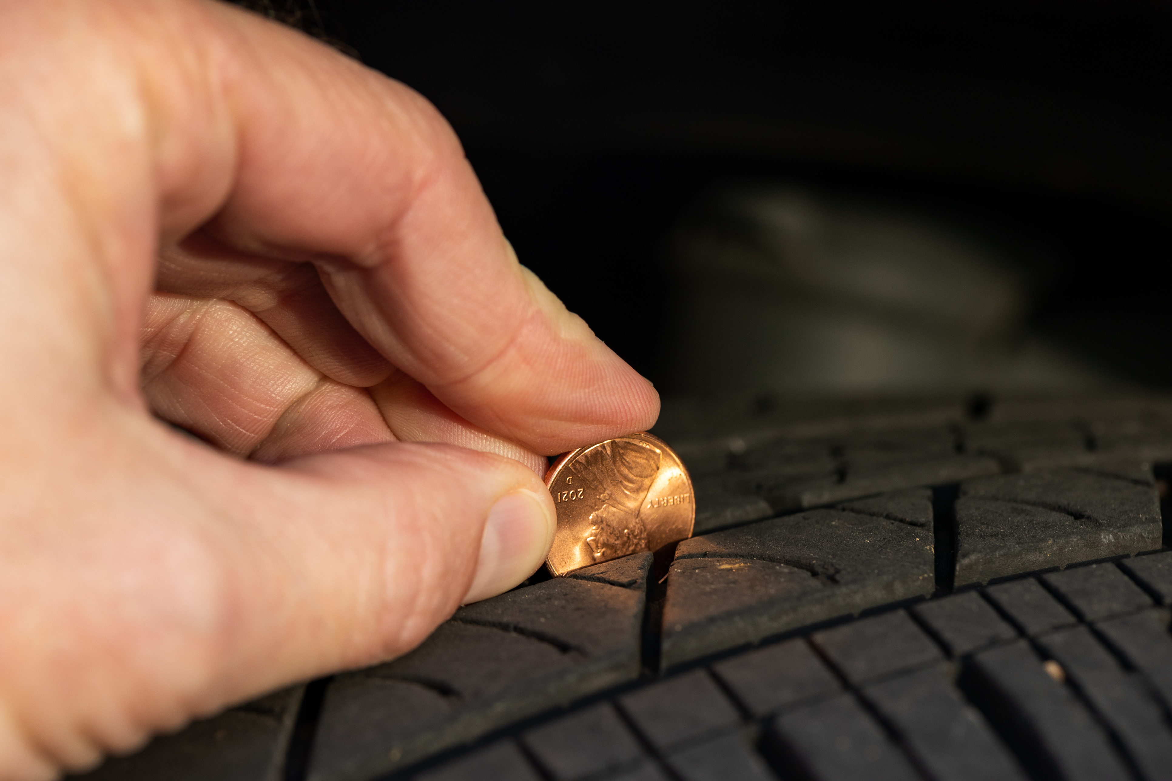 Someone checking their tire tread depth with a penny. 