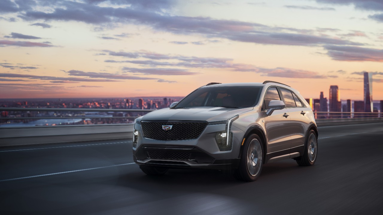 A new Cadillac XT4 luxury SUV is driving at dusk.