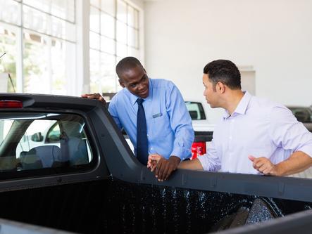 car salesman looks at truck with customer