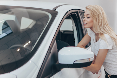 Pretty woman looking inside a new car