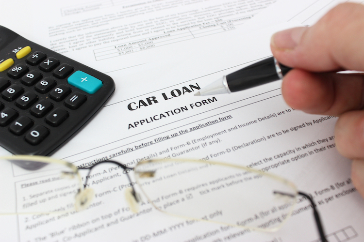 Picture of a car loan application with pen and calculator