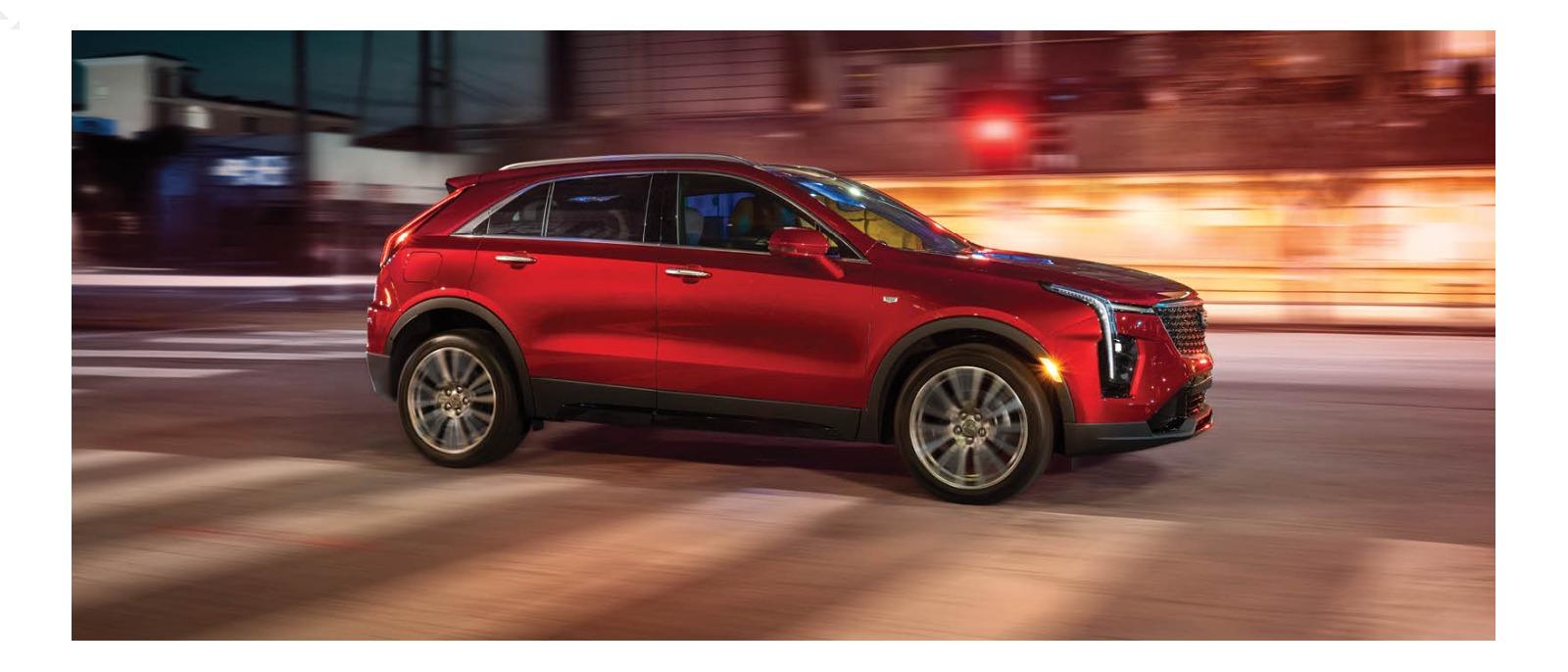 Welcome to McLaughlin Cadillac - a metallic red Cadillac SUV driving on a street