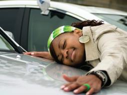 woman laying across the hood of a car and smiling with her arms out