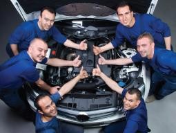 service techs in front of car with hood open giving thumbs up