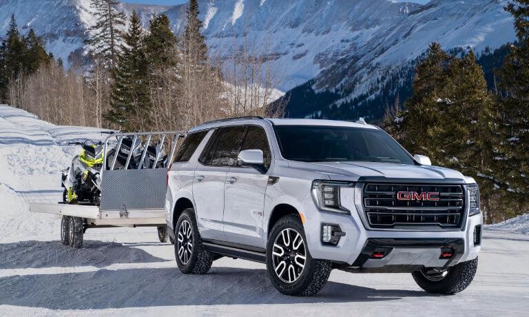 2024 GMC Yukon towing snow mobiles in snow