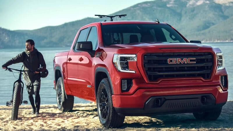 GMC Sierra 1500 parked on a beach with mountain biker