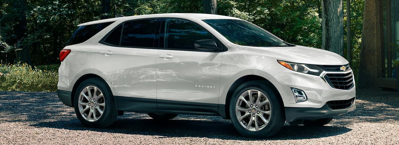 A white 2020 Chevy Equinox is parked on gravel in a wooded area after leaving a Chevy dealer near me.