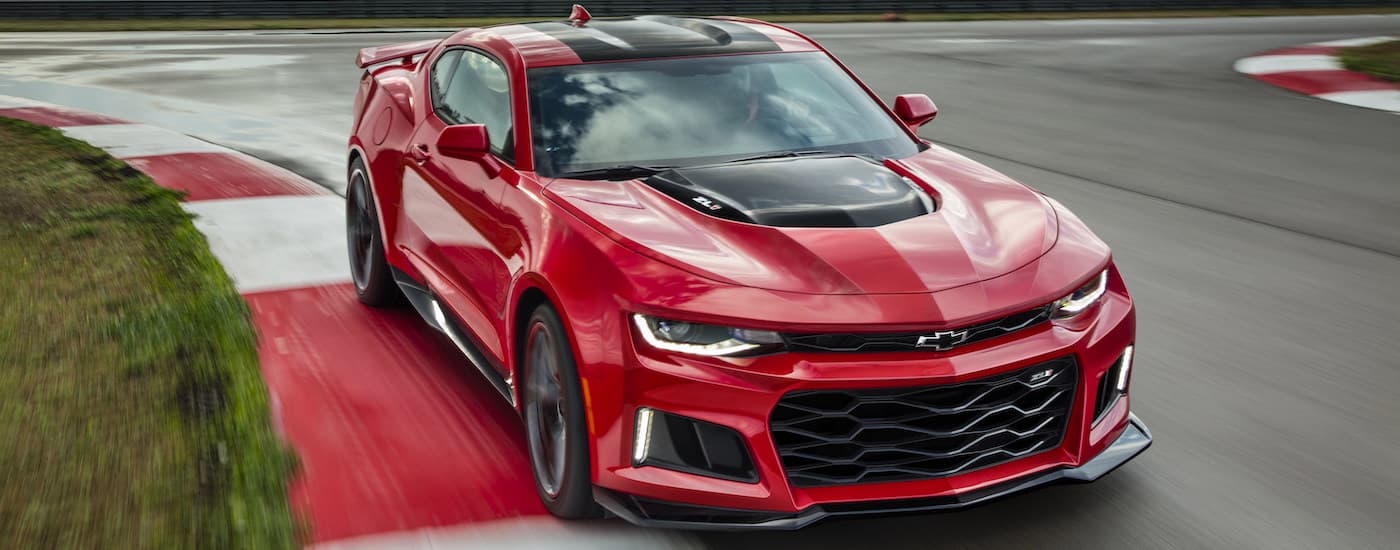 A red 2018 Chevy Camaro ZL1 is shown driving on a race track after visiting a certified pre-owned Chevy dealer.