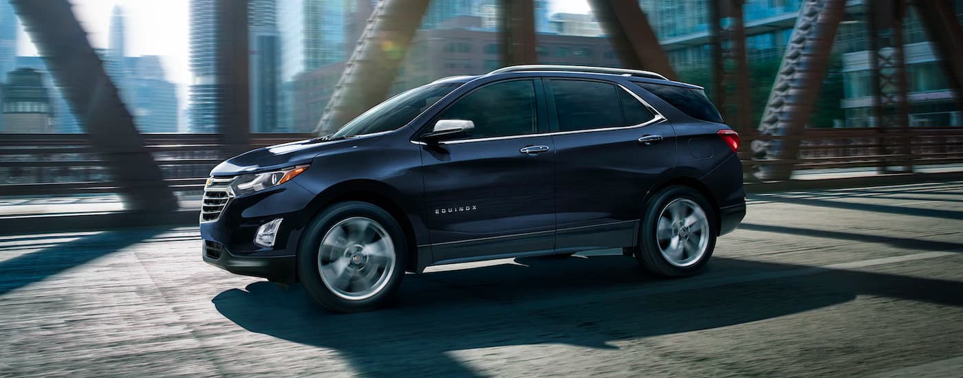 A blue 2019 Chevy Equinox is shown driving over a bridge after visiting an Elizabeth used car dealer.