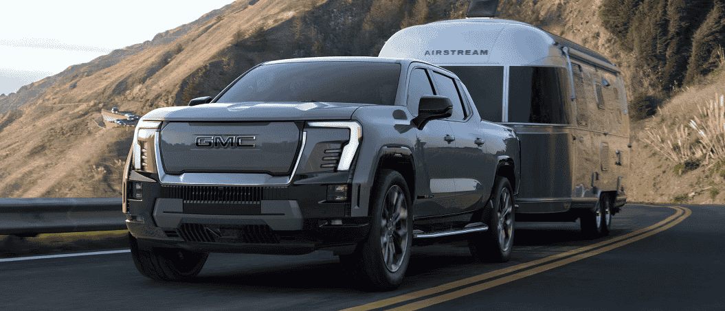 The 2025 GMC Sierra EV Denali tows a trailer behind it.