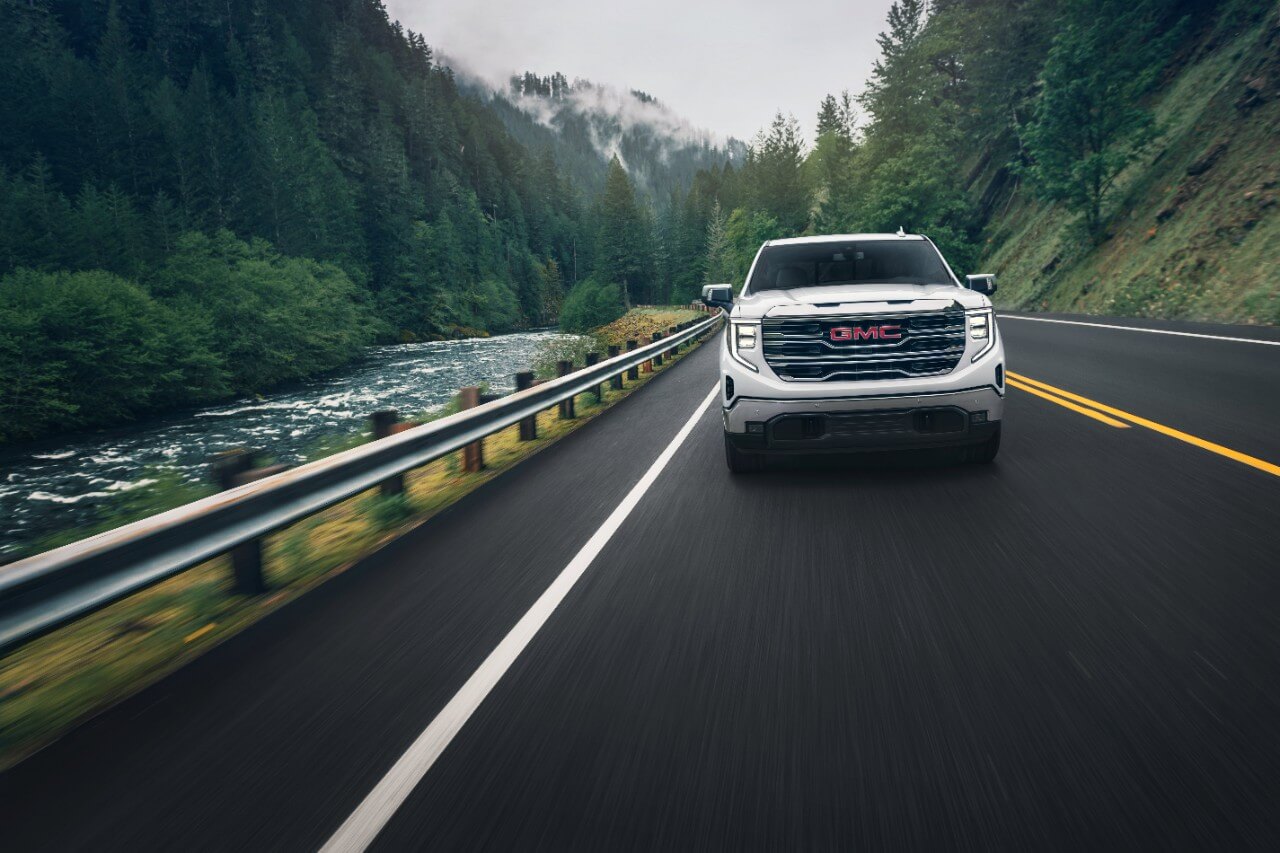 A white 2024 GMC Sierra 1500 is driving down the road.