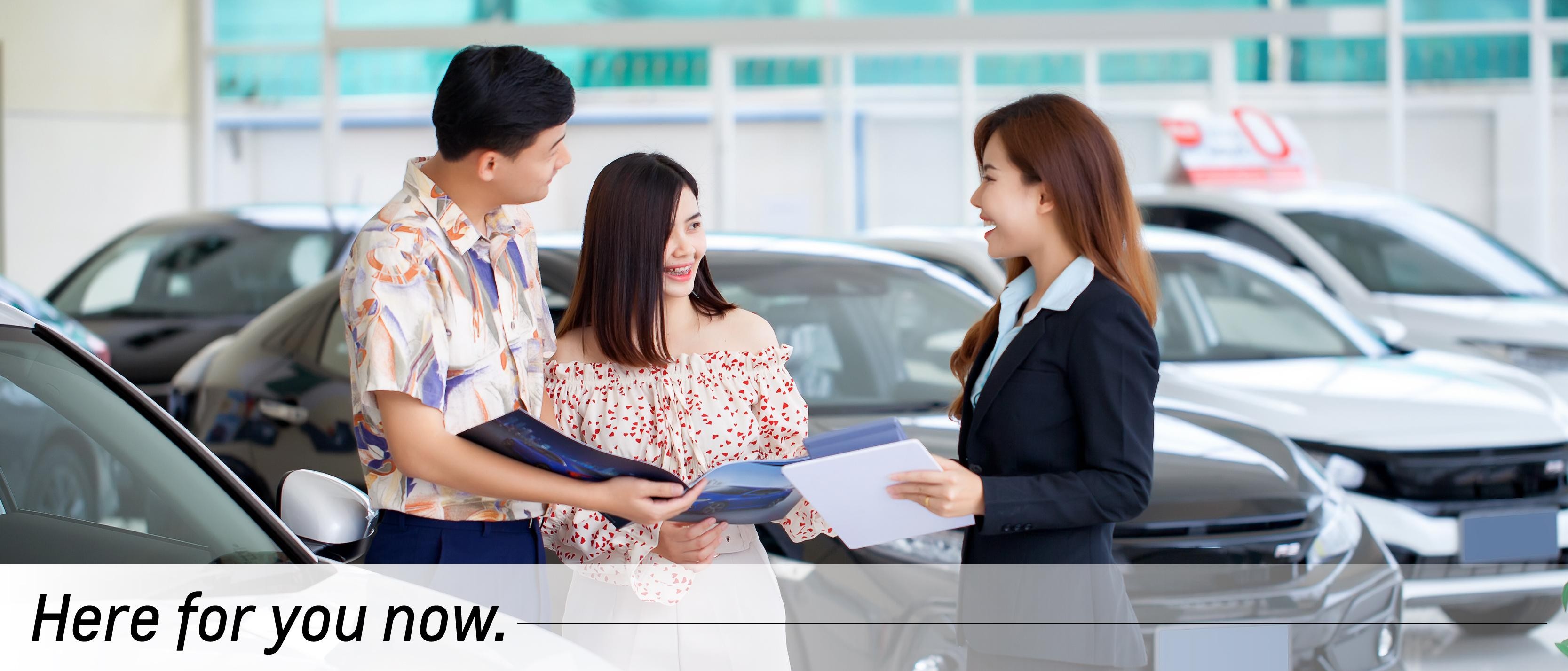 A salesmen shows a woman a vehicle.