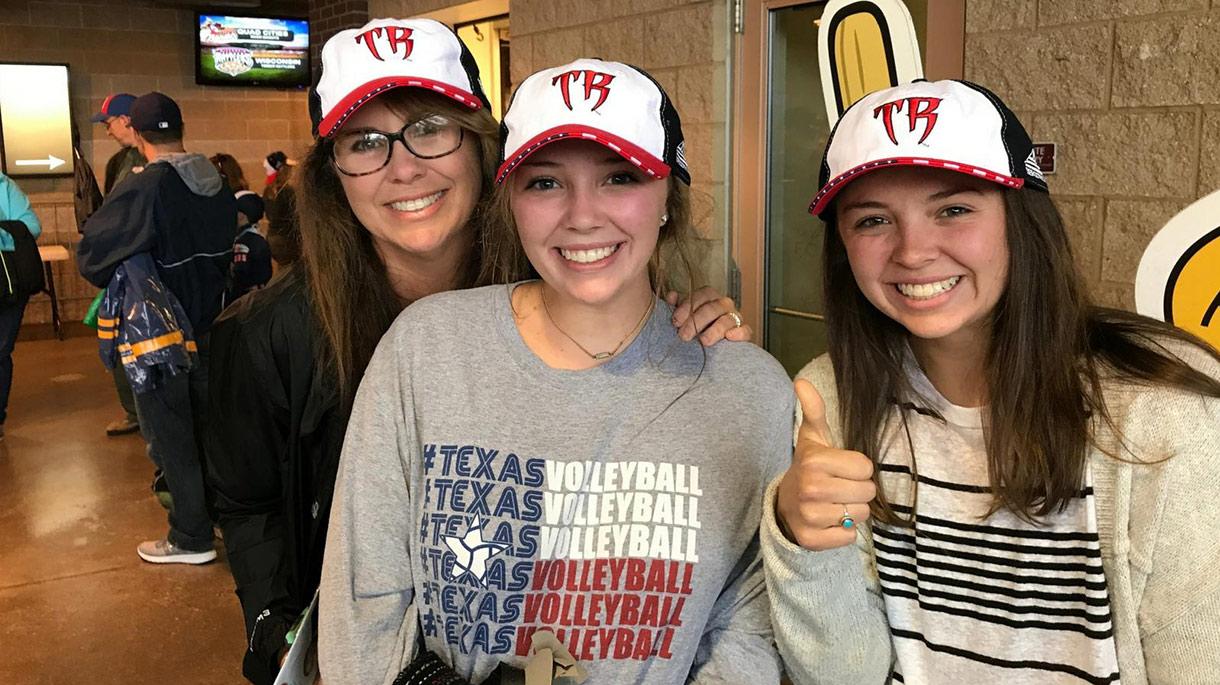 Three women smiling with Wisconsin Timber Rattlers hats