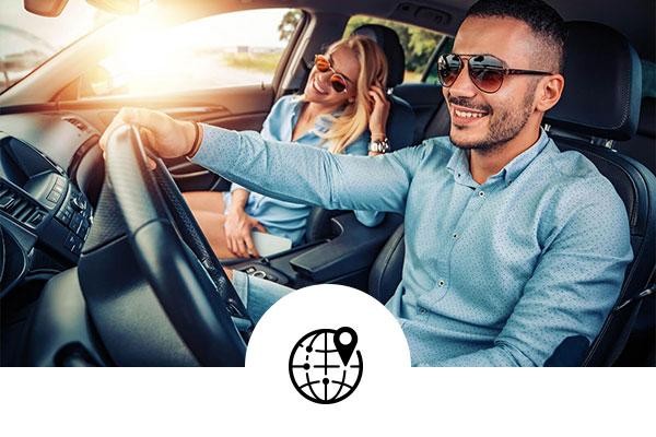 Happy couple wearing sunglasses while driving in a car with a globe and map icon