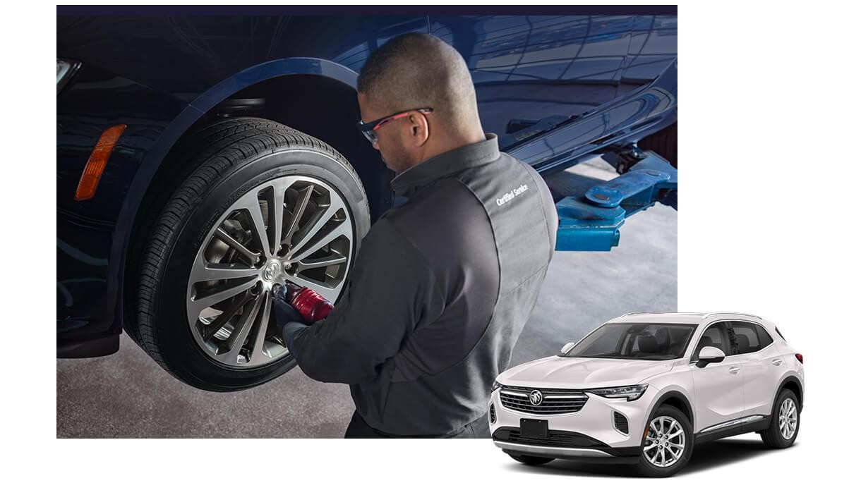 White Buick Envision with a service technician working on a vehicle in the background