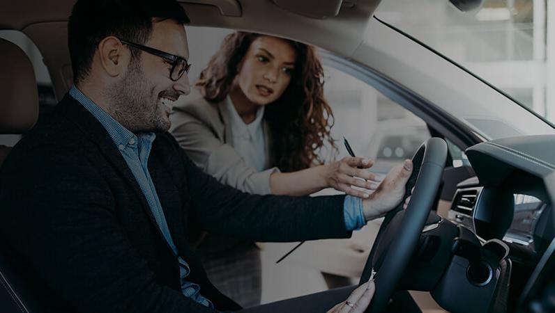 Sales associate showing a customer a new vehicle in a dealership showroom