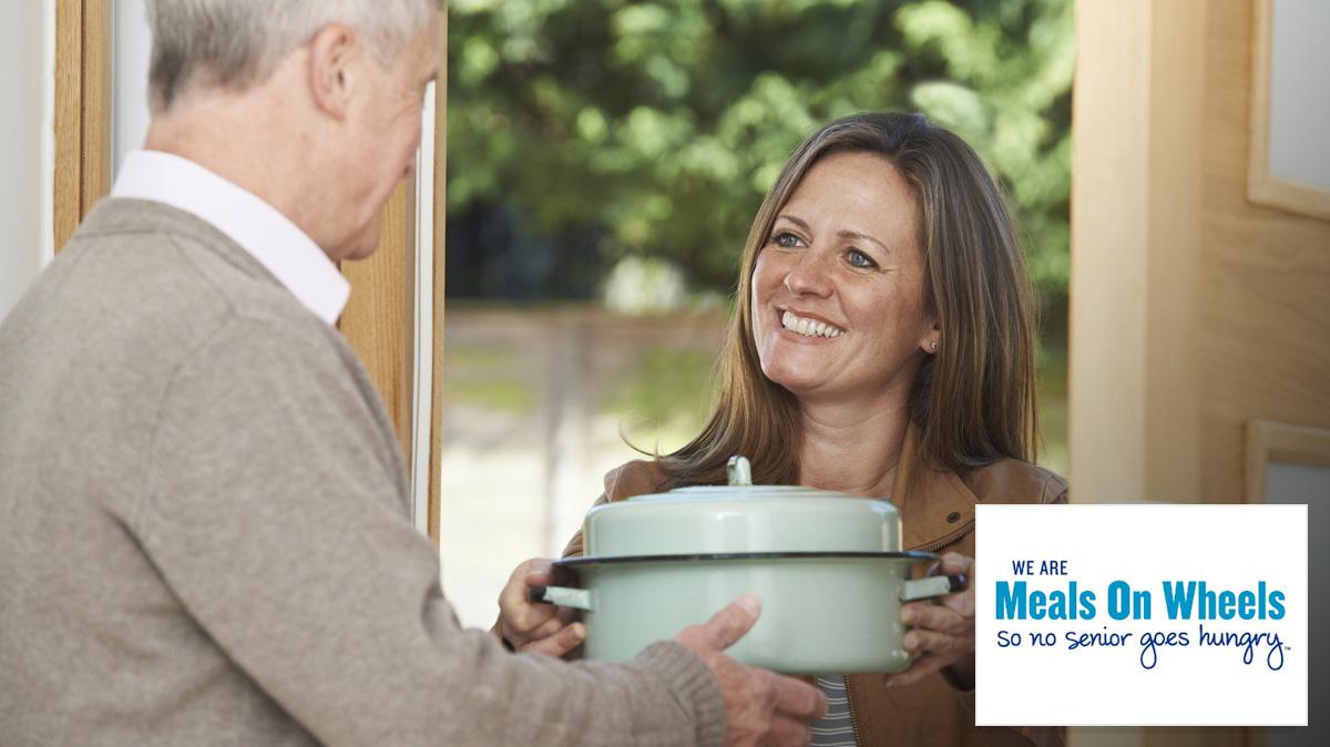 Woman delivering food to an elderly man - Meals on wheels