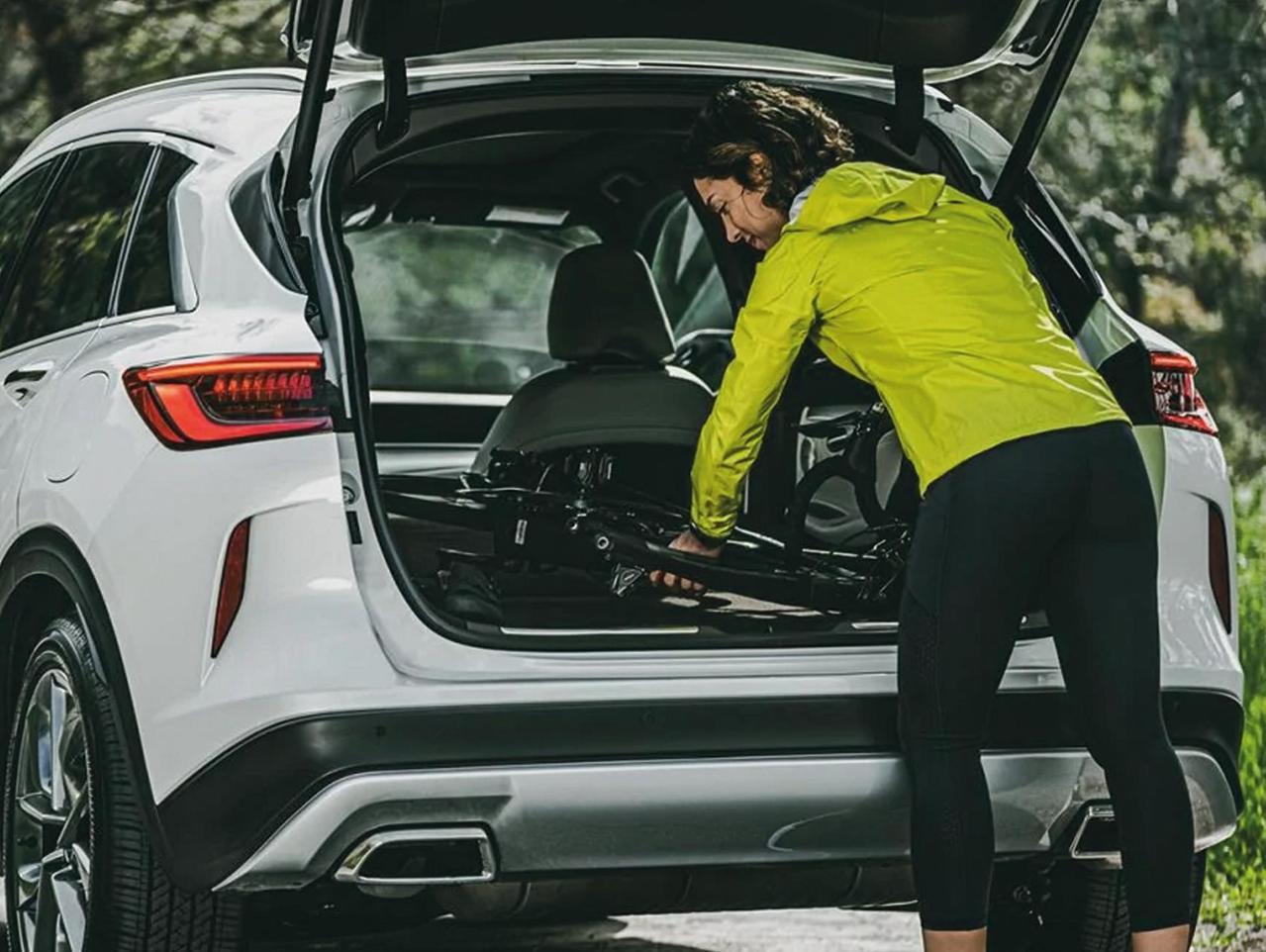 Image of woman loading a mountain bike into the trunk of a QX50.