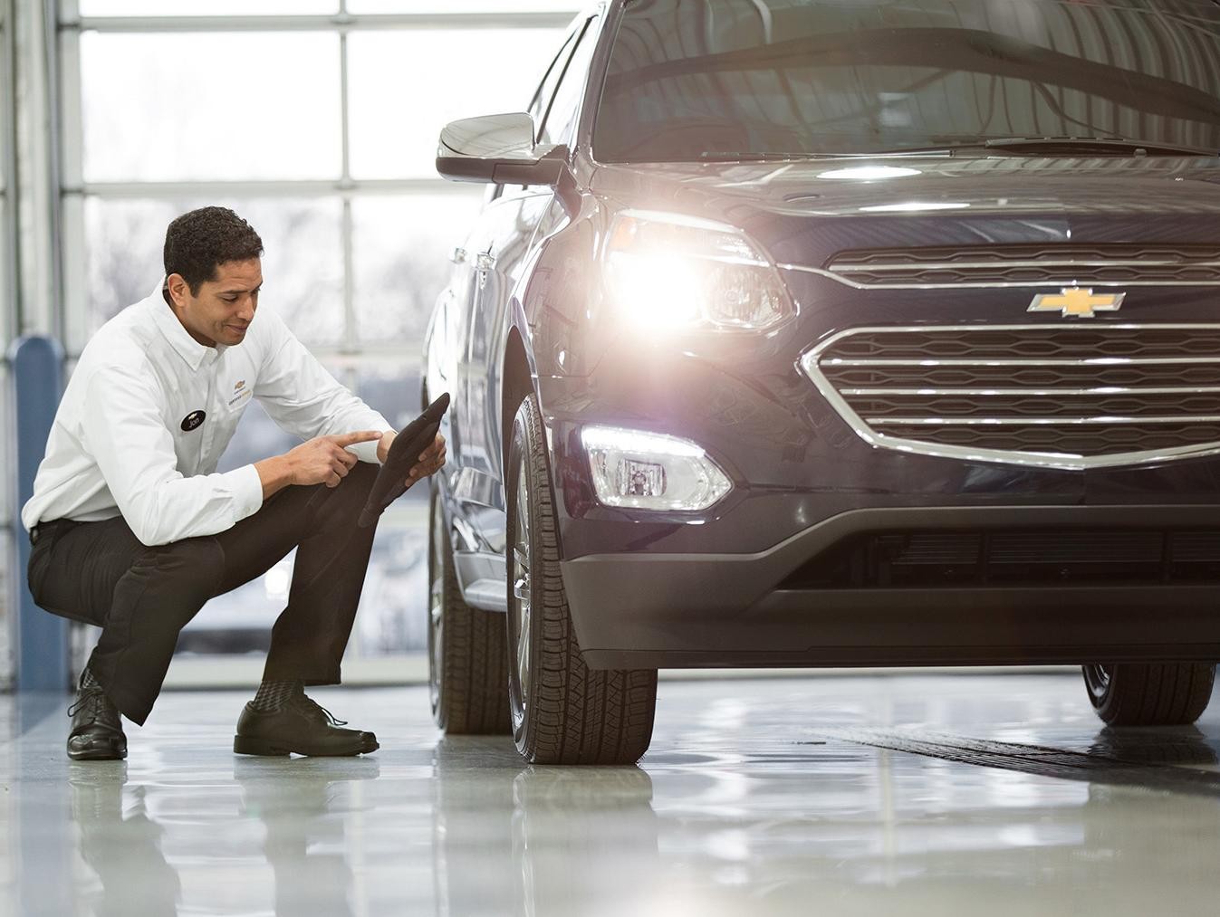 Chevrolet, Buick Service technician checking on tires of SUV