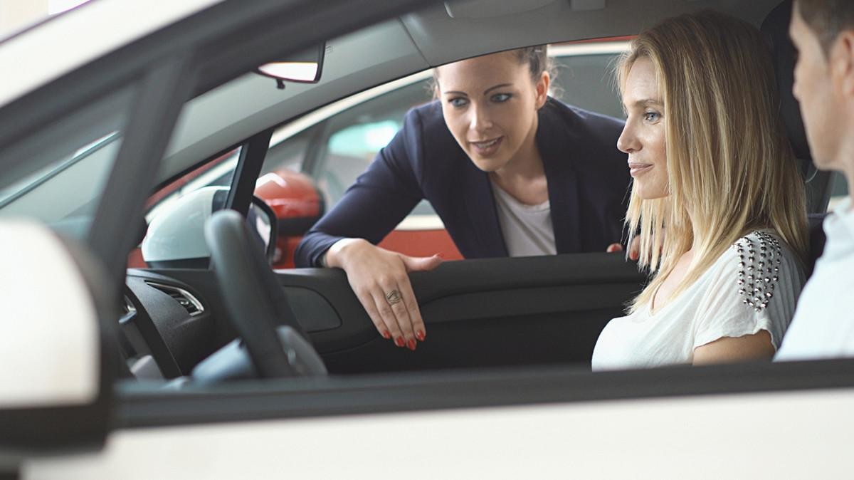 A sale consultant showing a couple interior details of a car. 