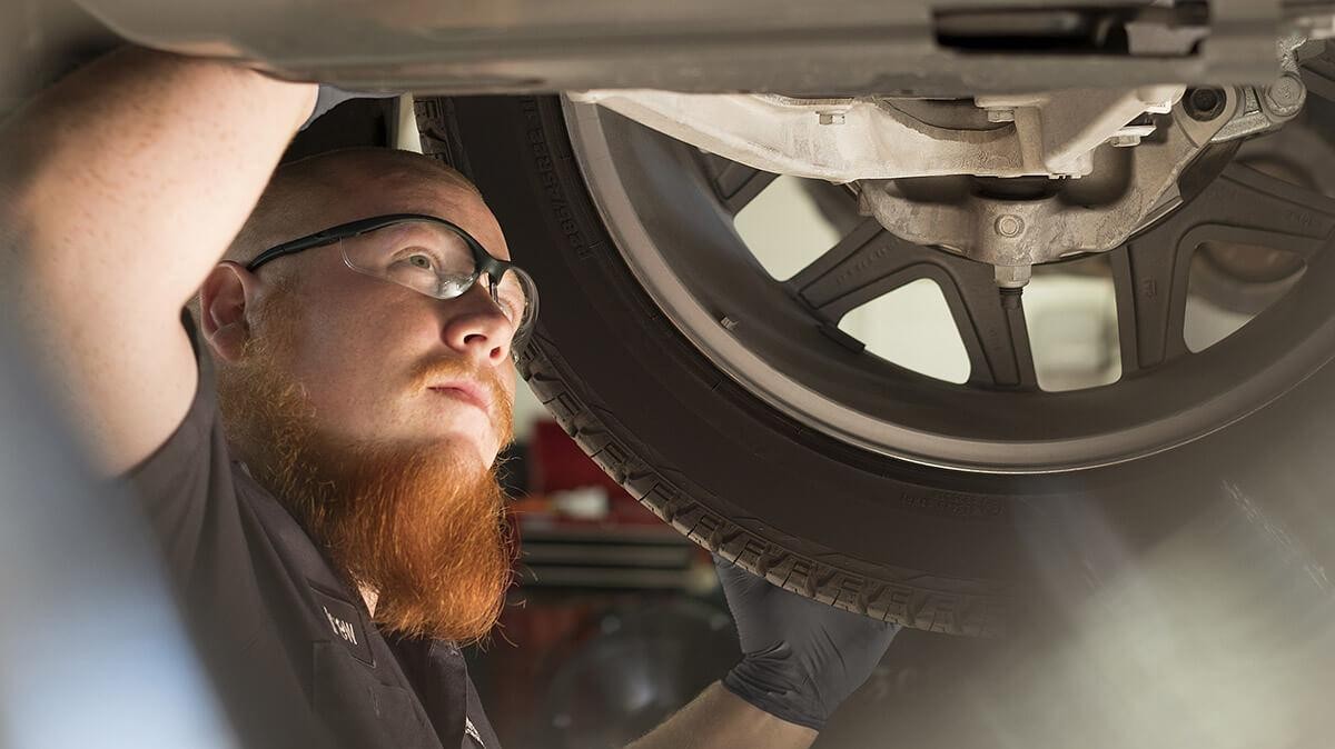 A mechanic working under a vehicle on a lift.