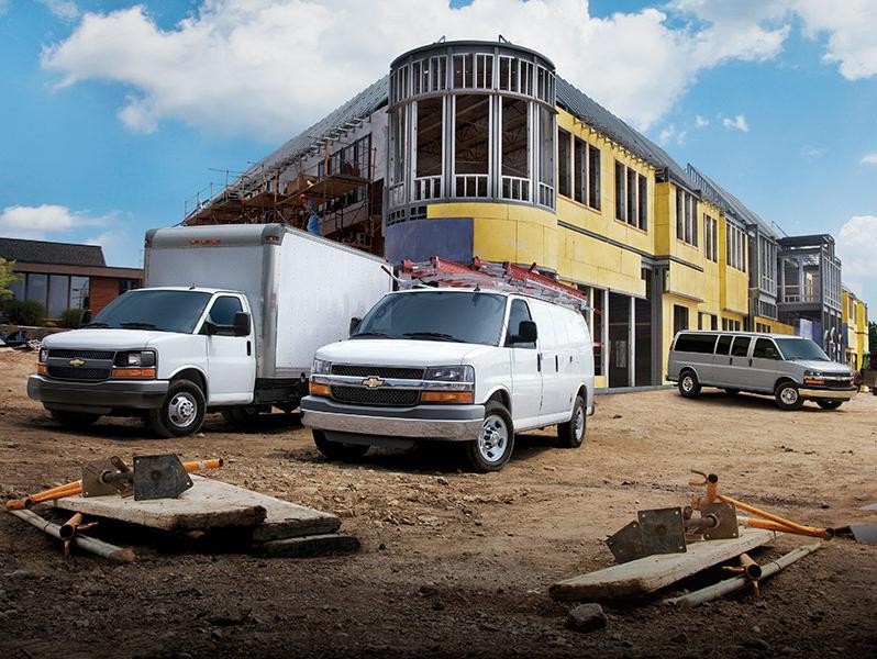 Lineup of Chevy work vans at a building construction site.