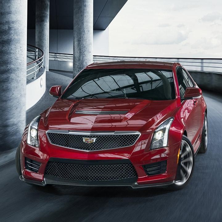 A red Cadillac ATS-V driving down a parking ramp.