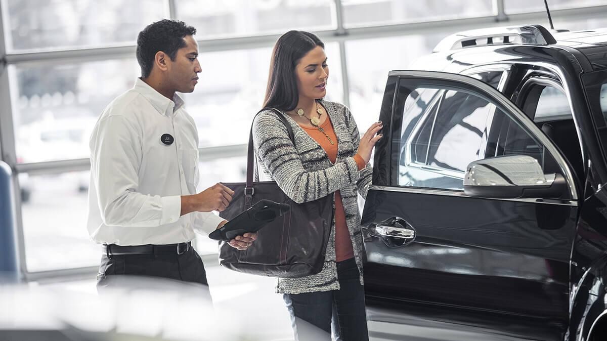 Car salesman showing a woman a new vehicle.