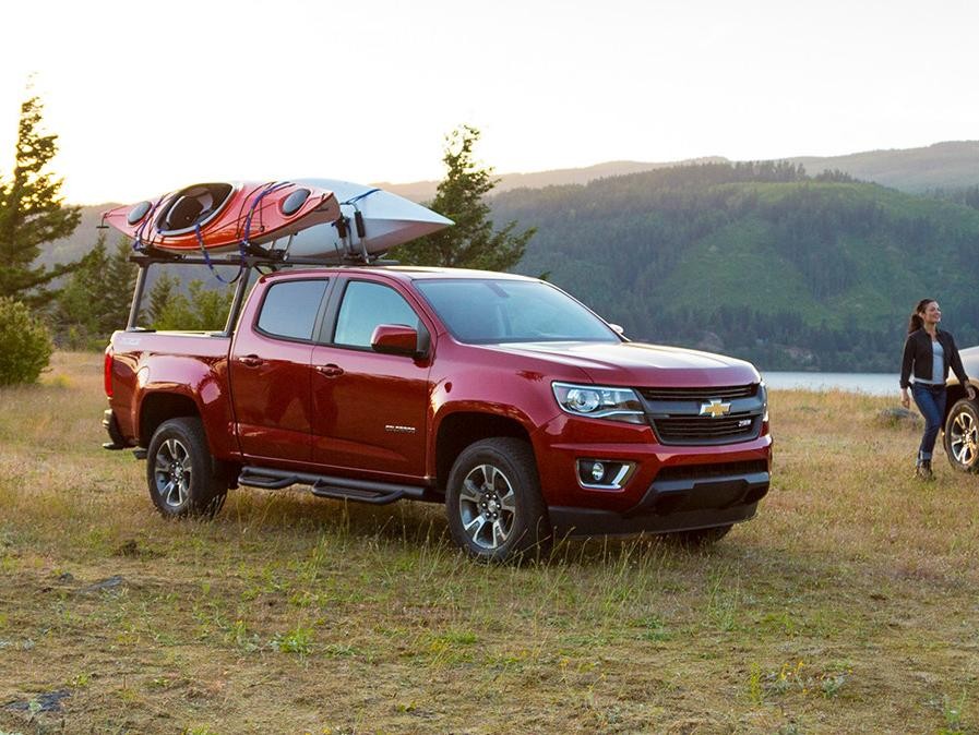 Kayak enthusiasts setting up with their Chevy Colorado trucks by a lake.