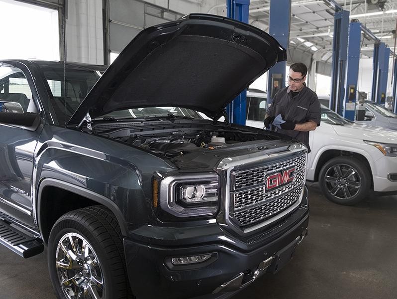 Service technician inspecting a GMC Sierra 1500 Denali.