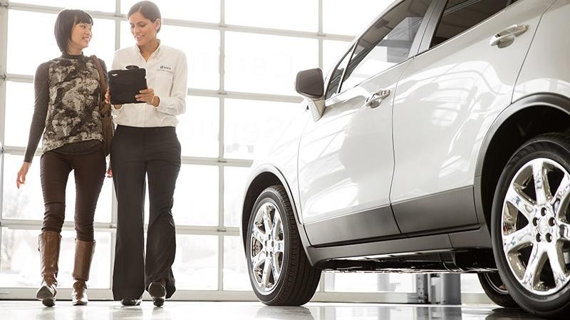 Service technician inspecting a Buick vehicle with a customer.