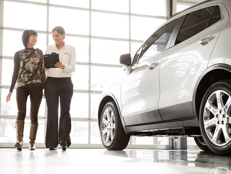 Service technician inspecting a Buick vehicle with a customer.