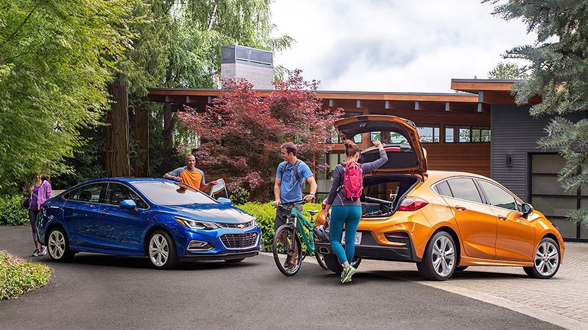 Two couples packing up their Chevy Cruze and Cruze Hatchback for a day of hiking and biking.