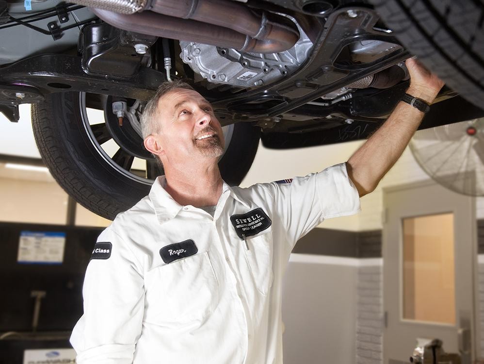 Sewell Technician examining the bottom of a vehicle