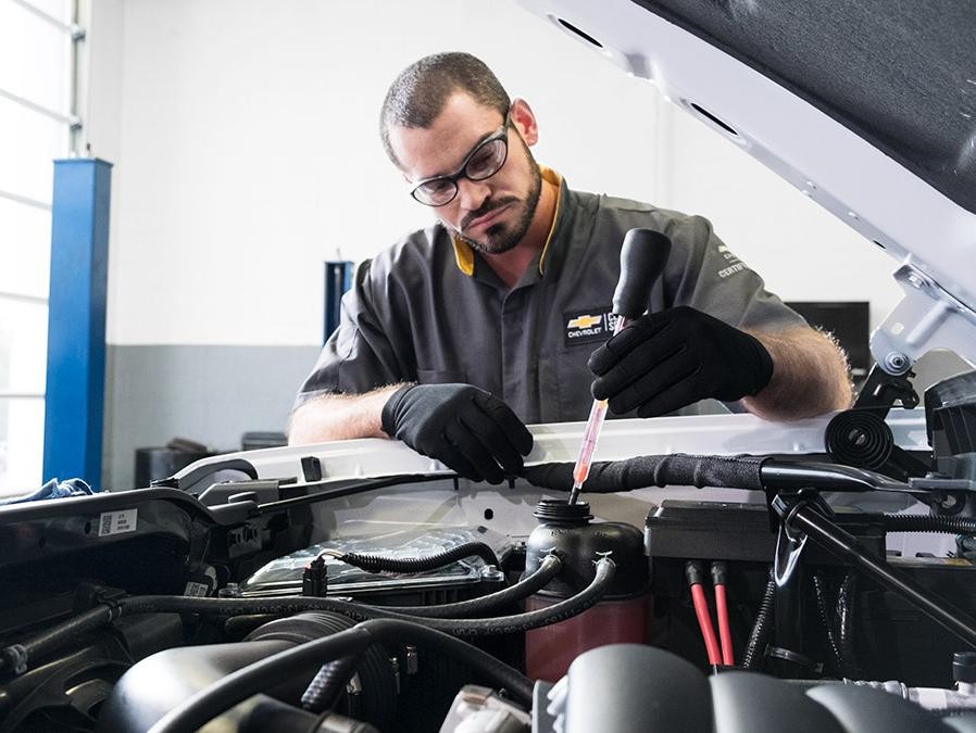 Service technician working under the hood of a car.